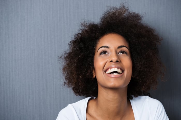 Laughing African American woman with an afro hairstyle and good sense of humor smiling as she tilts her head back to look into the air